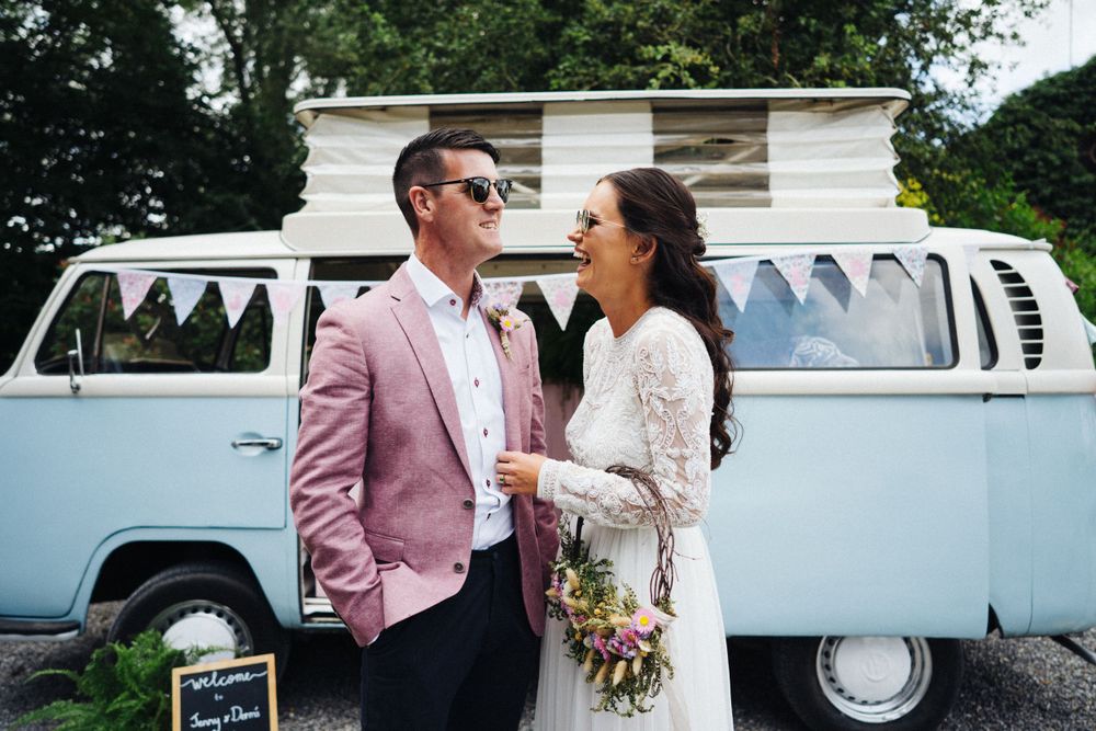 Romantic moment captured in front of baby blue vintage VW van with bunting decorations.