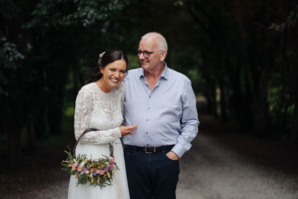 A tender moment captured between two people on a forest path during a wedding celebration.