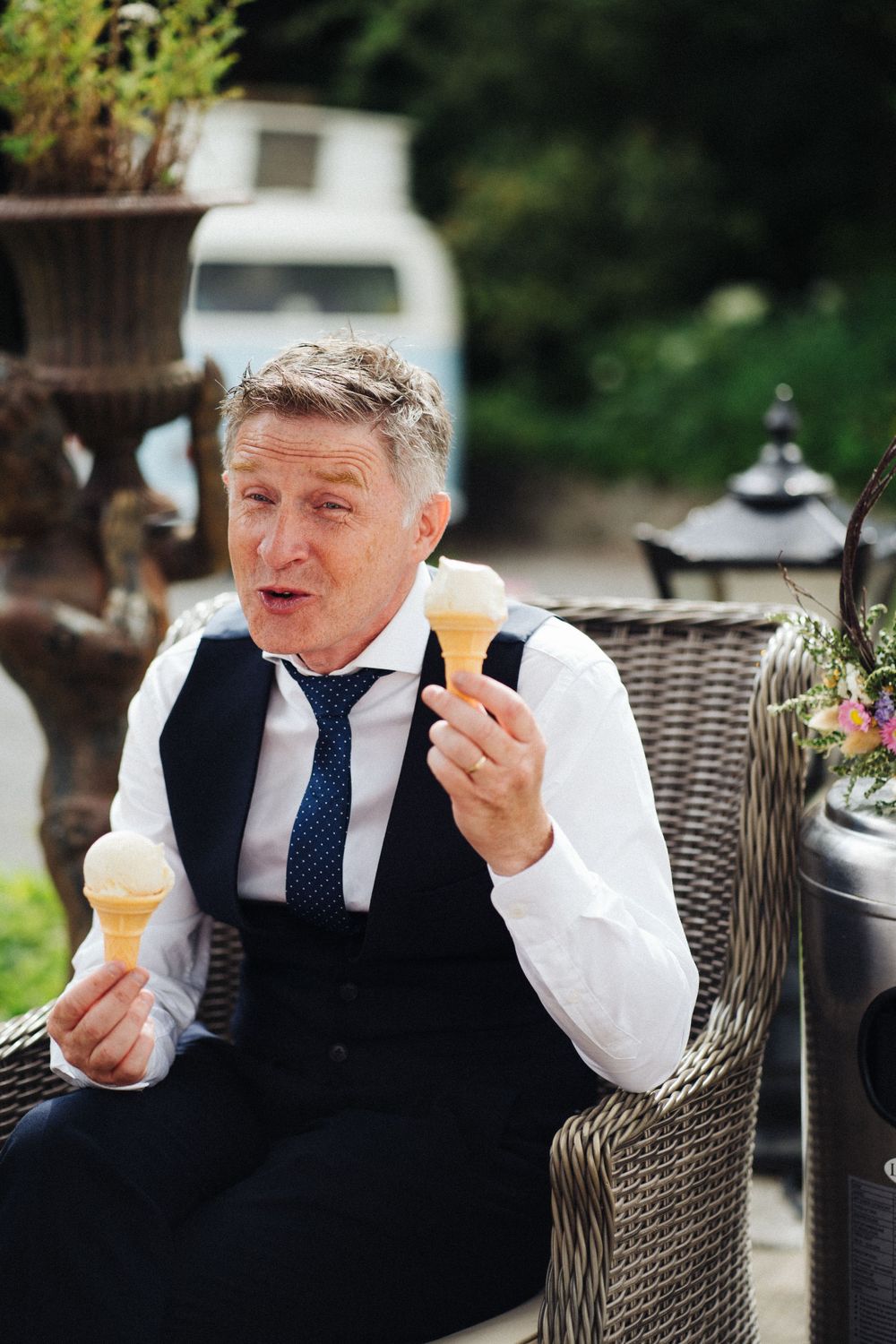 Wedding guest enjoying ice cream while relaxing in wicker furniture outdoors.