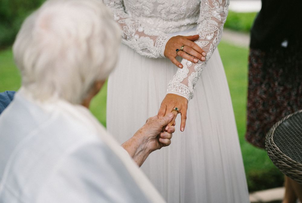 Close up detail shot of delicate lace sleeve and hands during wedding ceremony.