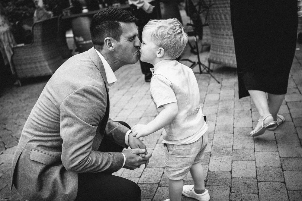 Tender black and white moment shared between a young child and adult on stone paving.