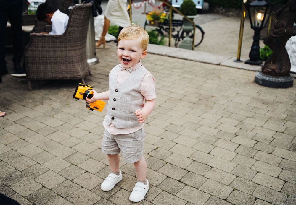 Joyful toddler laughing while playing with a toy on stone patio at outdoor event.