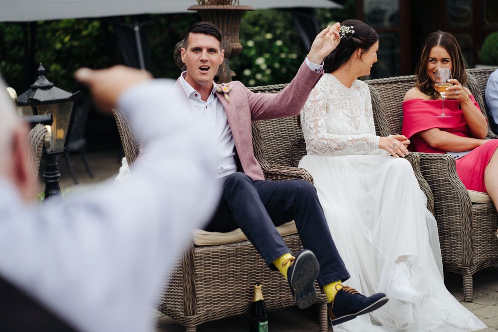 People seated in wicker furniture at an outdoor wedding celebration.