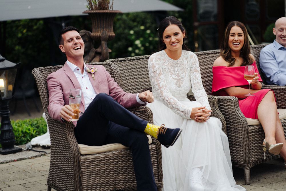 Newlyweds relaxing in wicker chairs during an outdoor reception.