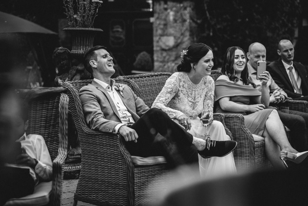 Wedding guests seated on wicker furniture during an outdoor reception.