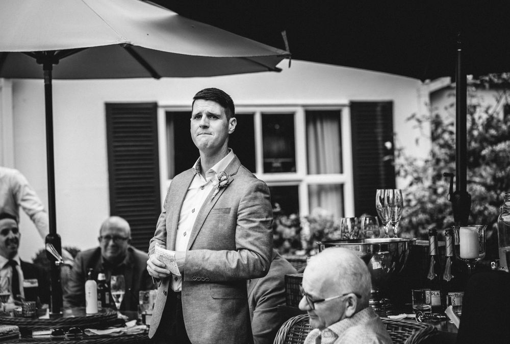 Black and white photo of a speaker addressing guests at an outdoor garden party.