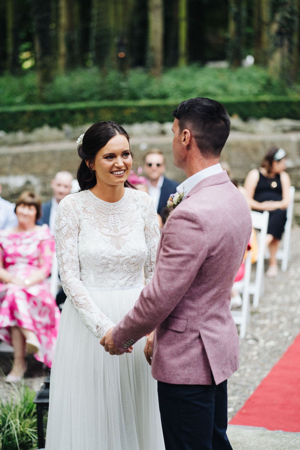 Intimate outdoor wedding ceremony moment between couple in front of seated guests.