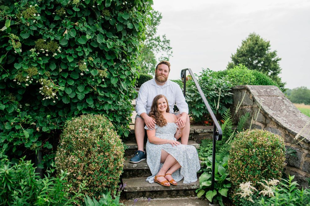 A playful moment captured on rustic stone steps surrounded by perfectly trimmed hedges and garden flowers.