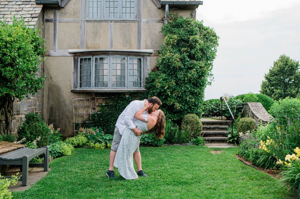 A romantic moment captured in a lush garden setting with stone architecture and blooming flowers.