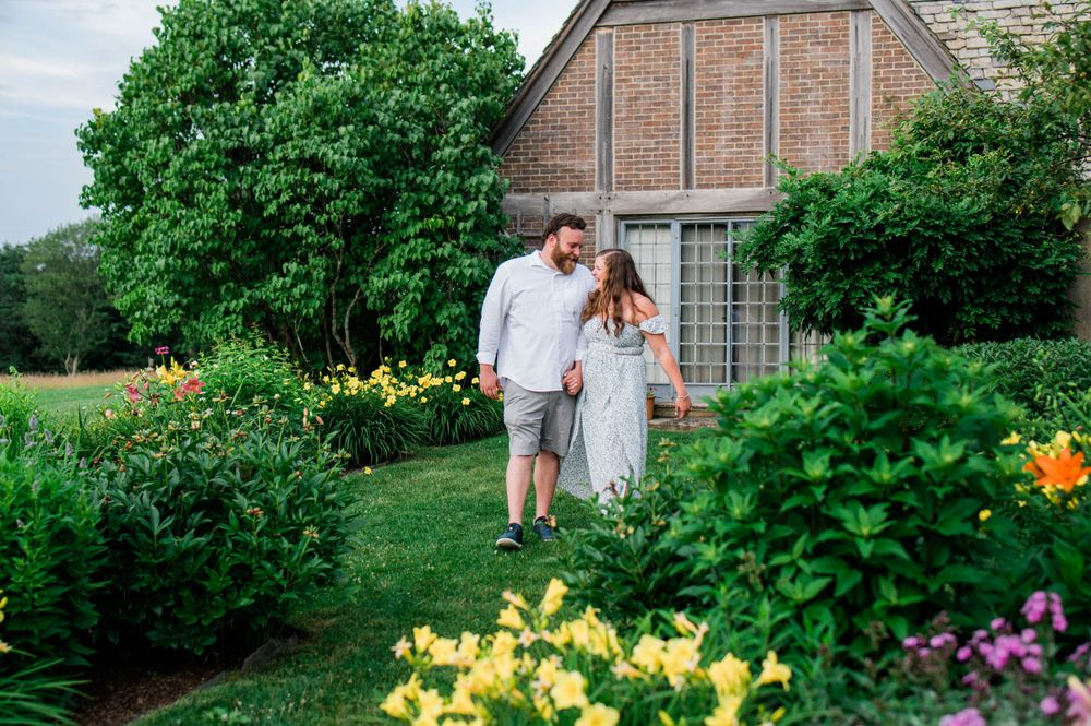 A couple shares a romantic moment amid yellow flowers and greenery outside a church.