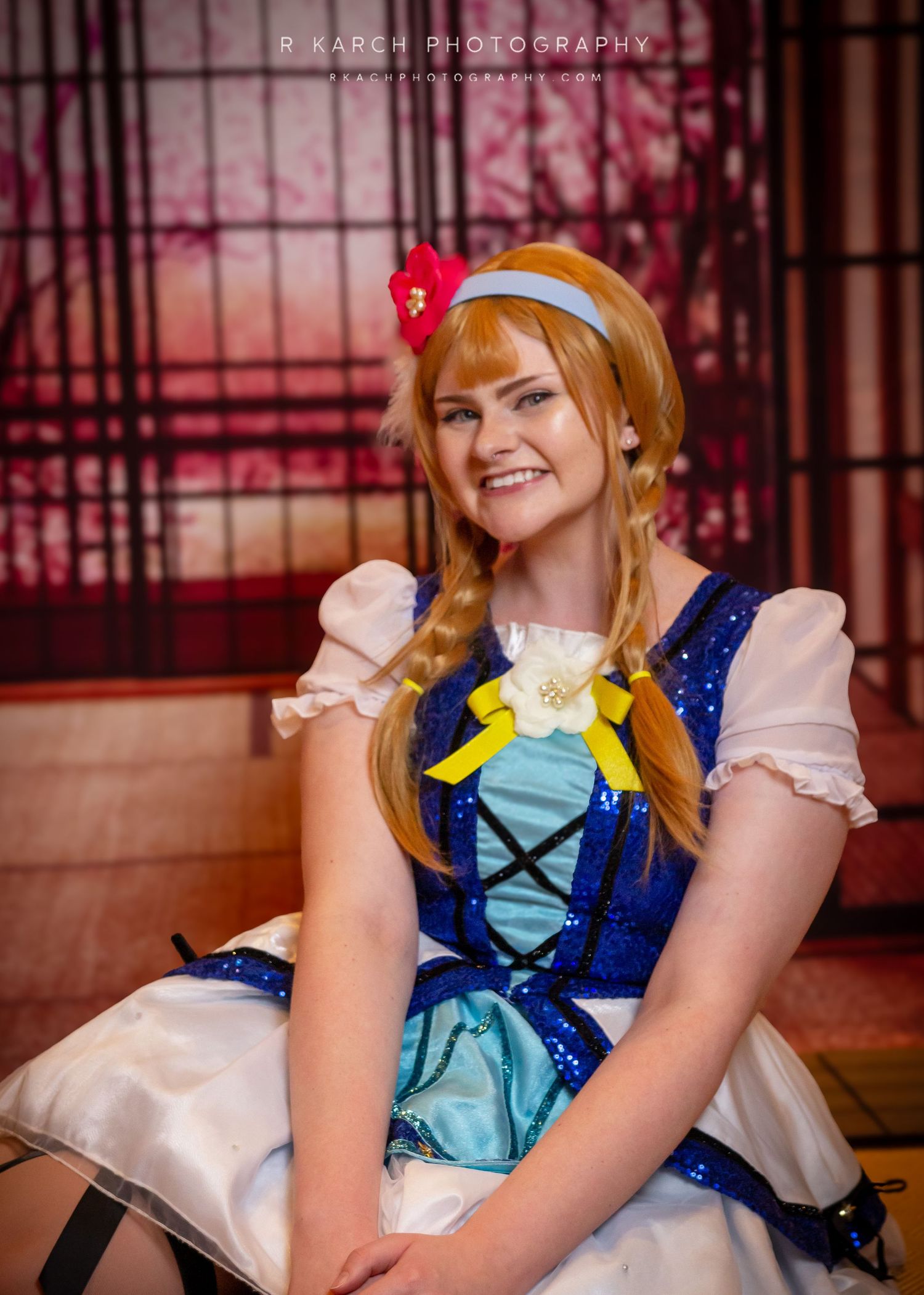 Cosplayer wearing blue and white dress with yellow bow in princess-style photoshoot.