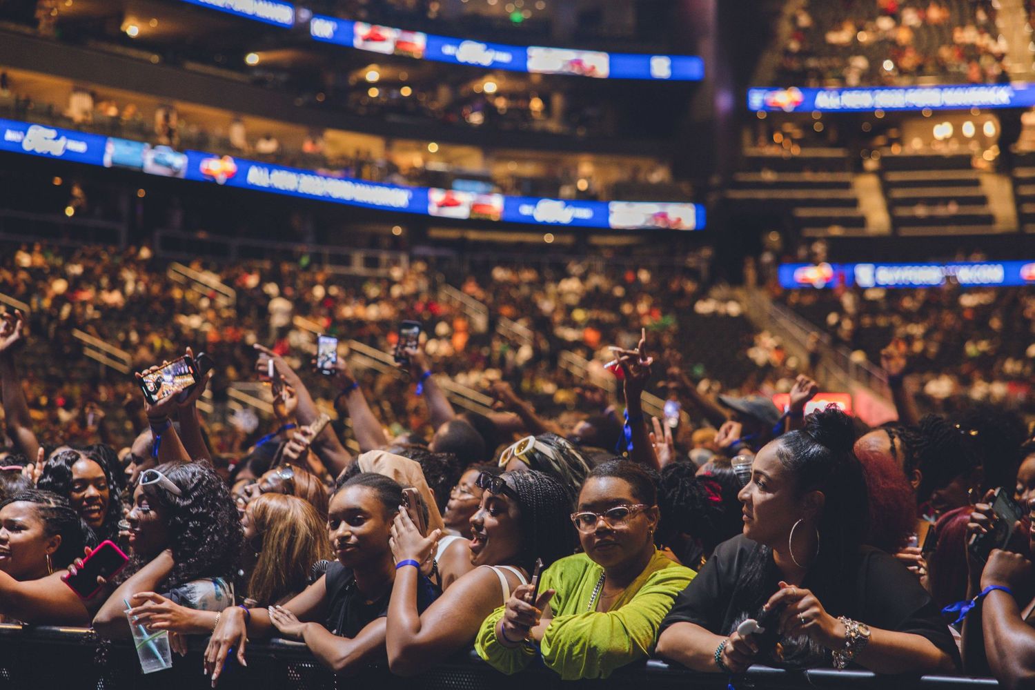 Large stadium crowd with raised hands enjoying a live entertainment event.