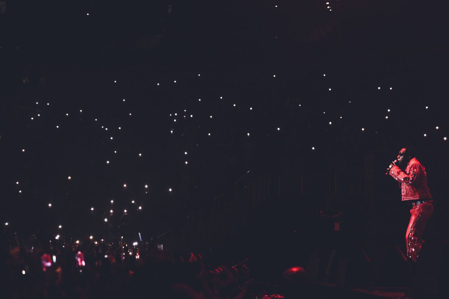 Starlit concert scene with scattered red lights against a dark background.
