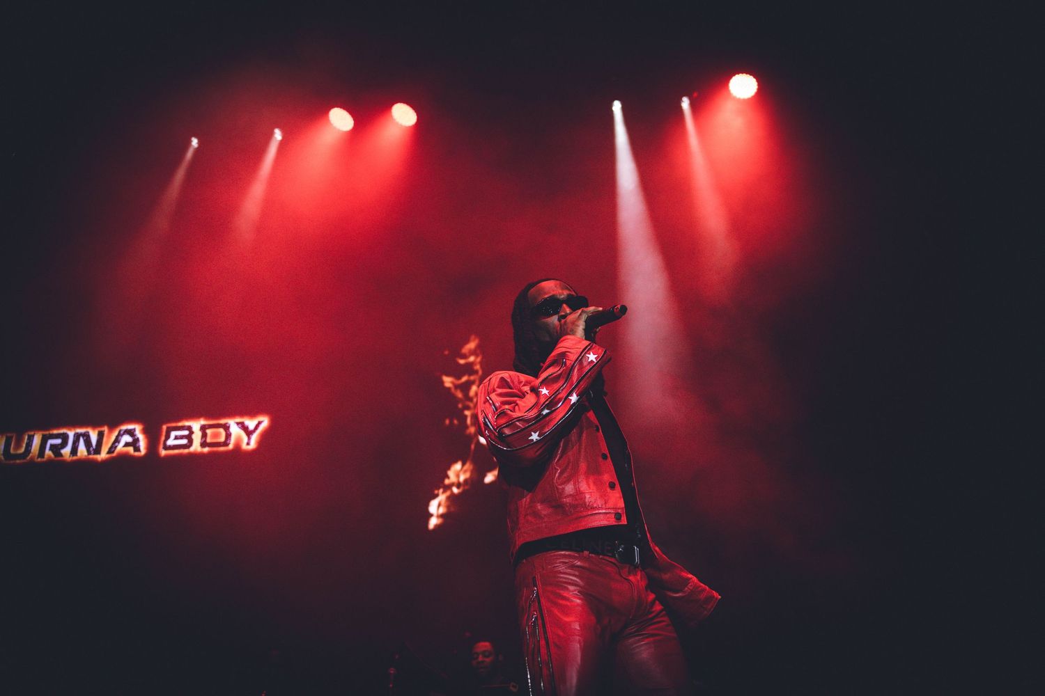 Concert stage illuminated with dramatic red lighting and fog effects during a live performance.