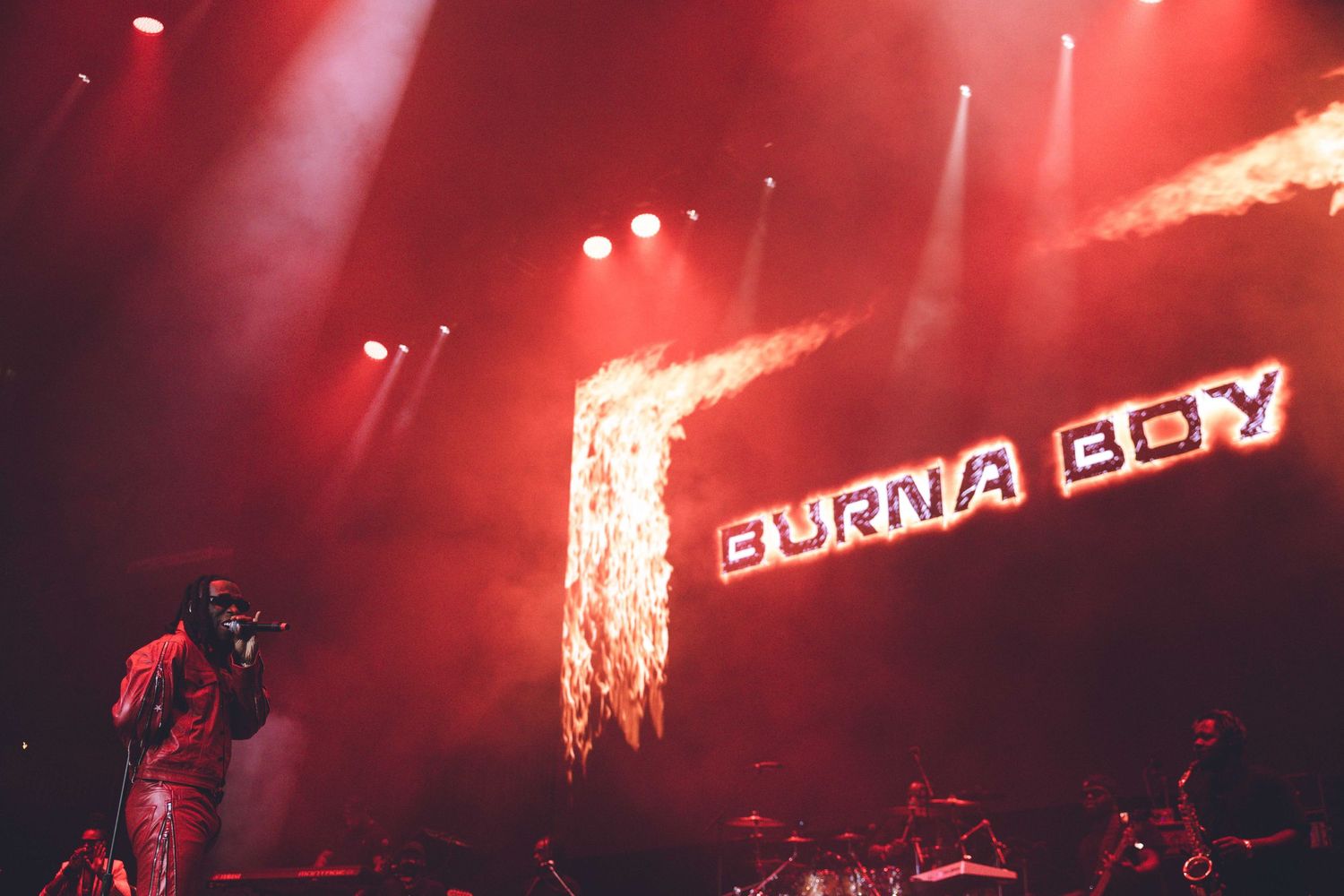 Stage performance featuring intense red lighting and dramatic pyrotechnic elements.