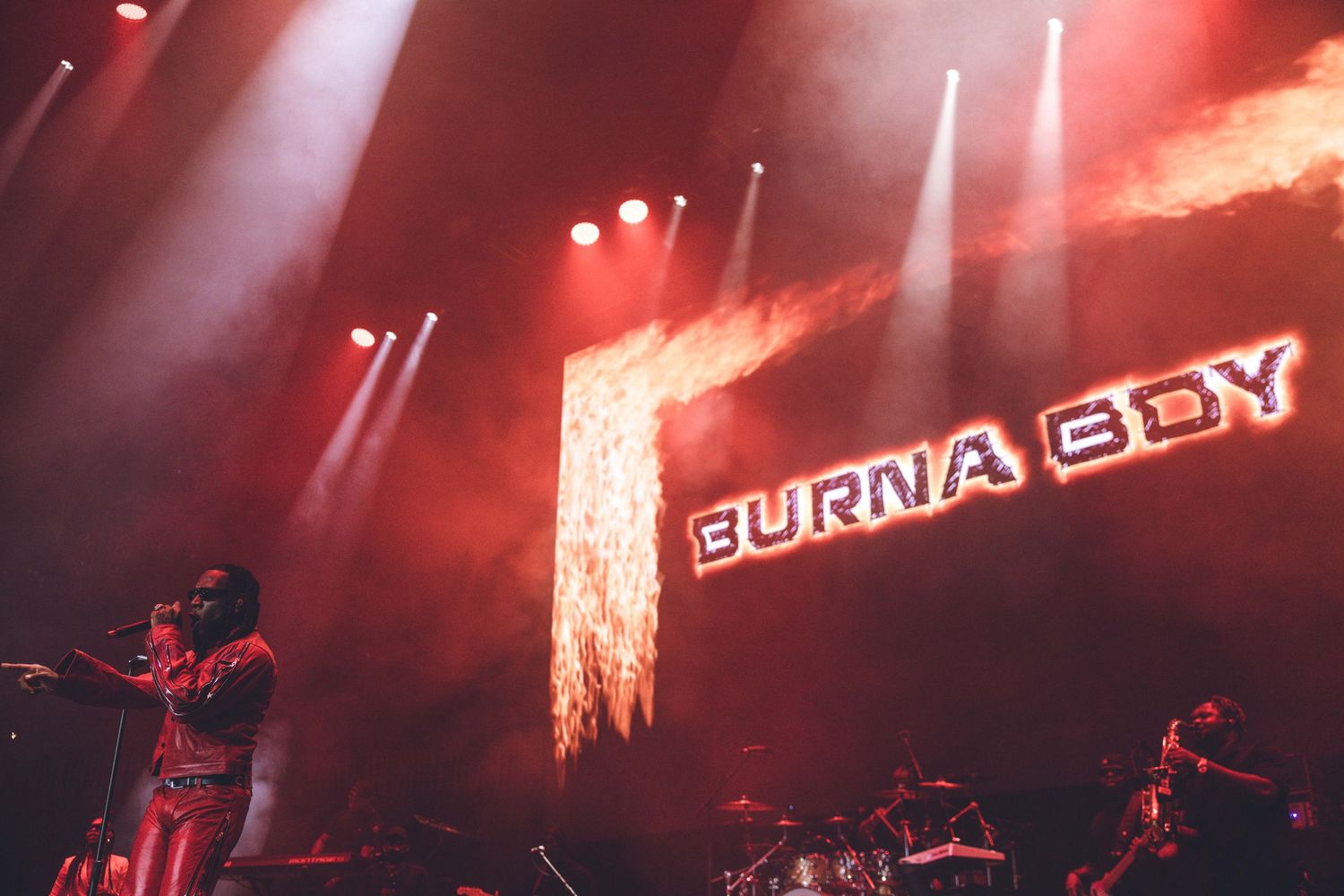Concert venue with fiery visual effects and illuminated Burna Boy branding on display.