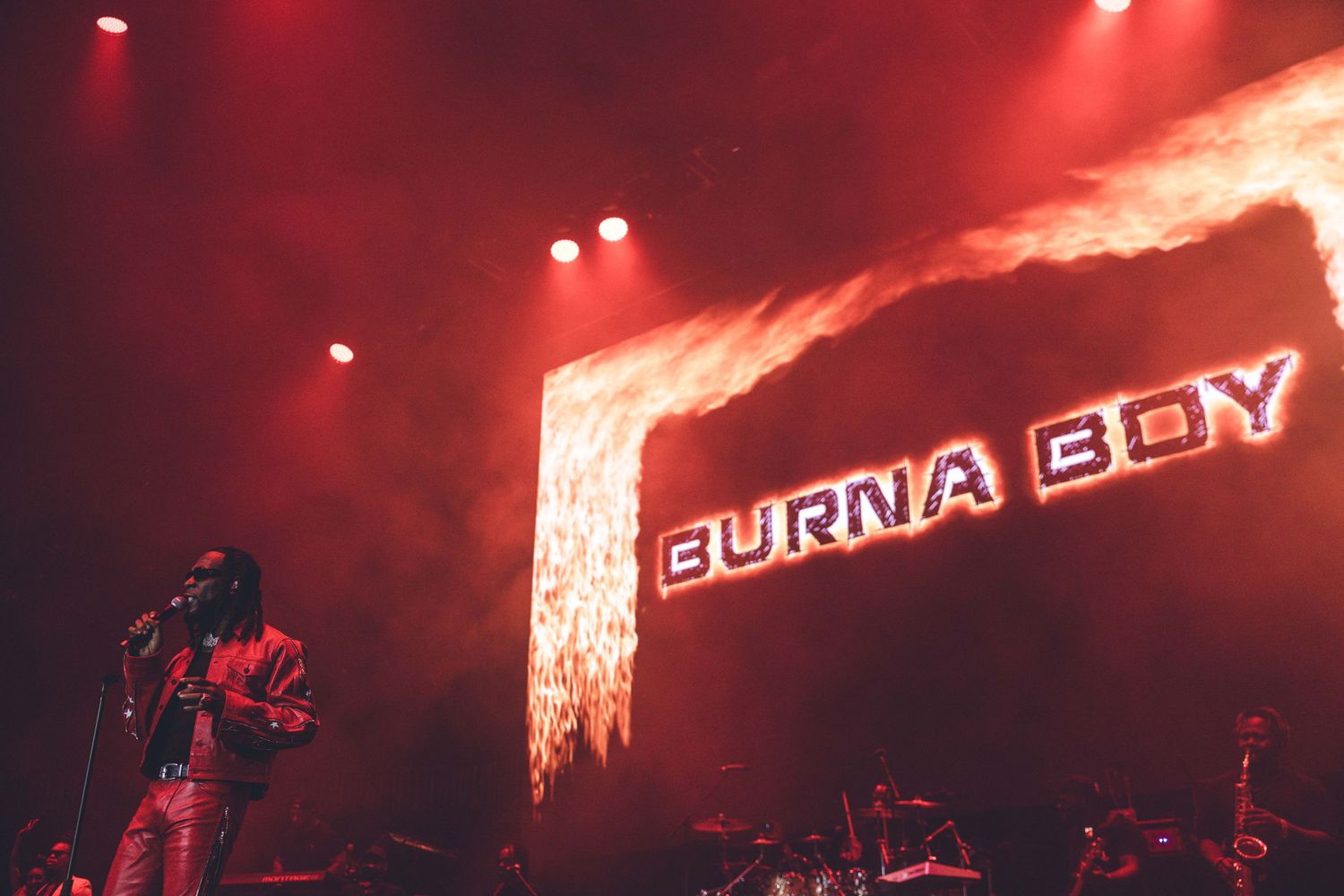 Burna Boy logo displayed on stage with dramatic red lighting and fire effects.