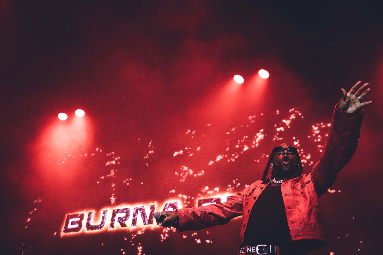Atmospheric concert venue bathed in deep red lighting with spotlights piercing through smoke.