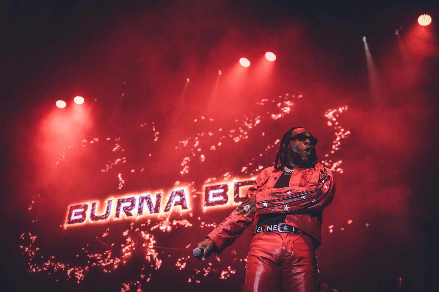 Concert stage illuminated with dramatic red lighting and fog effects during a dynamic performance.