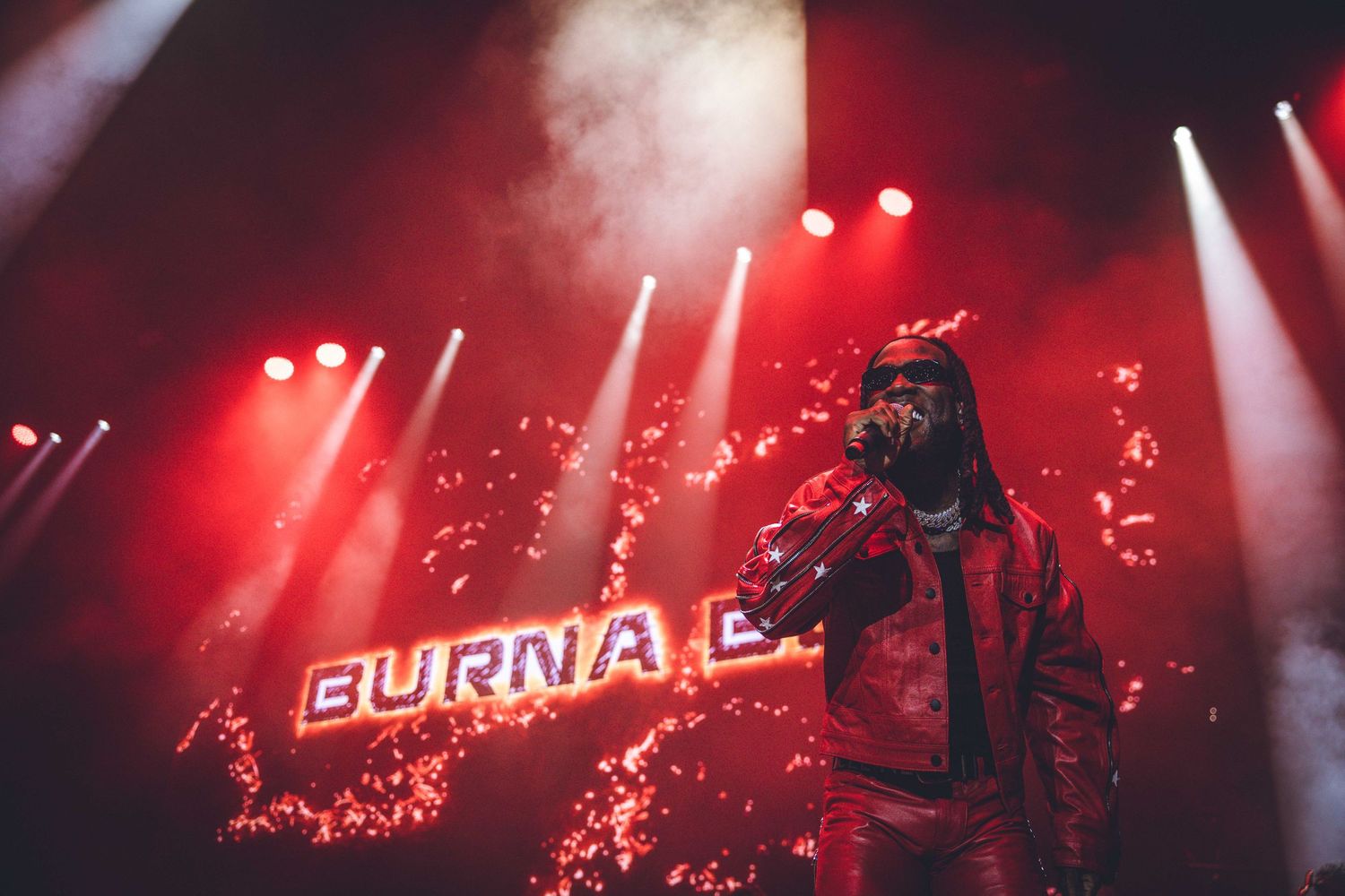 Concert stage lit in red with 'Burna B' text display and atmospheric lighting effects.