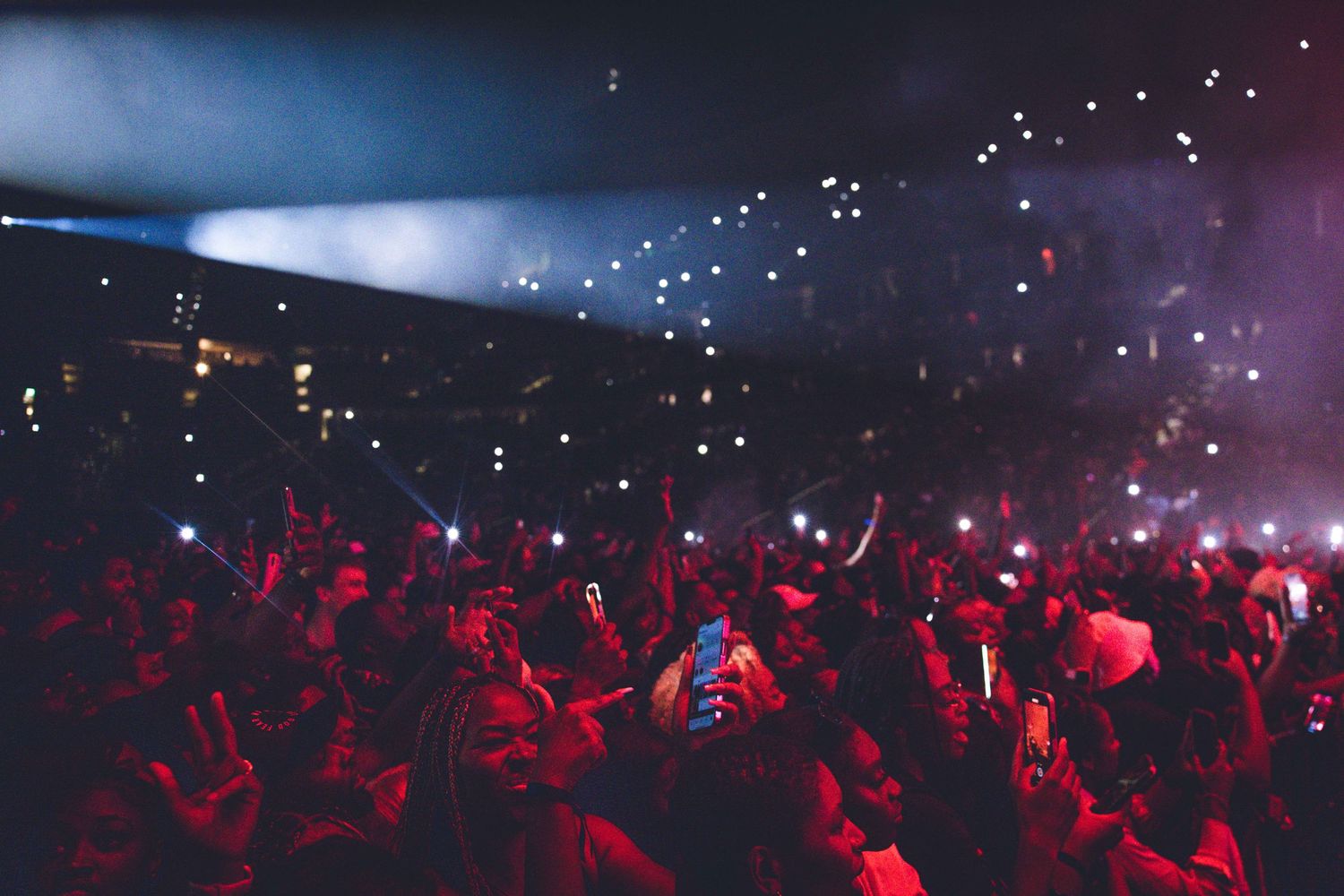 Concert crowd illuminated by red lights and spotlights during a high-energy performance.