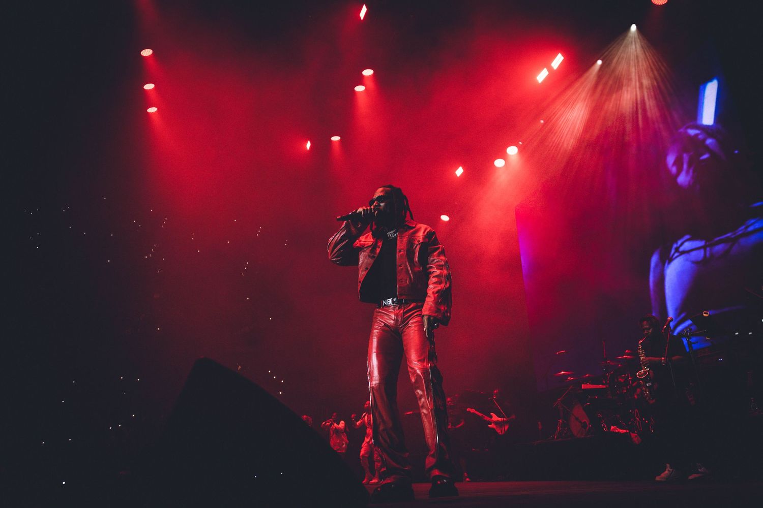 Concert performance silhouetted against intense red stage lighting and smoke effects.