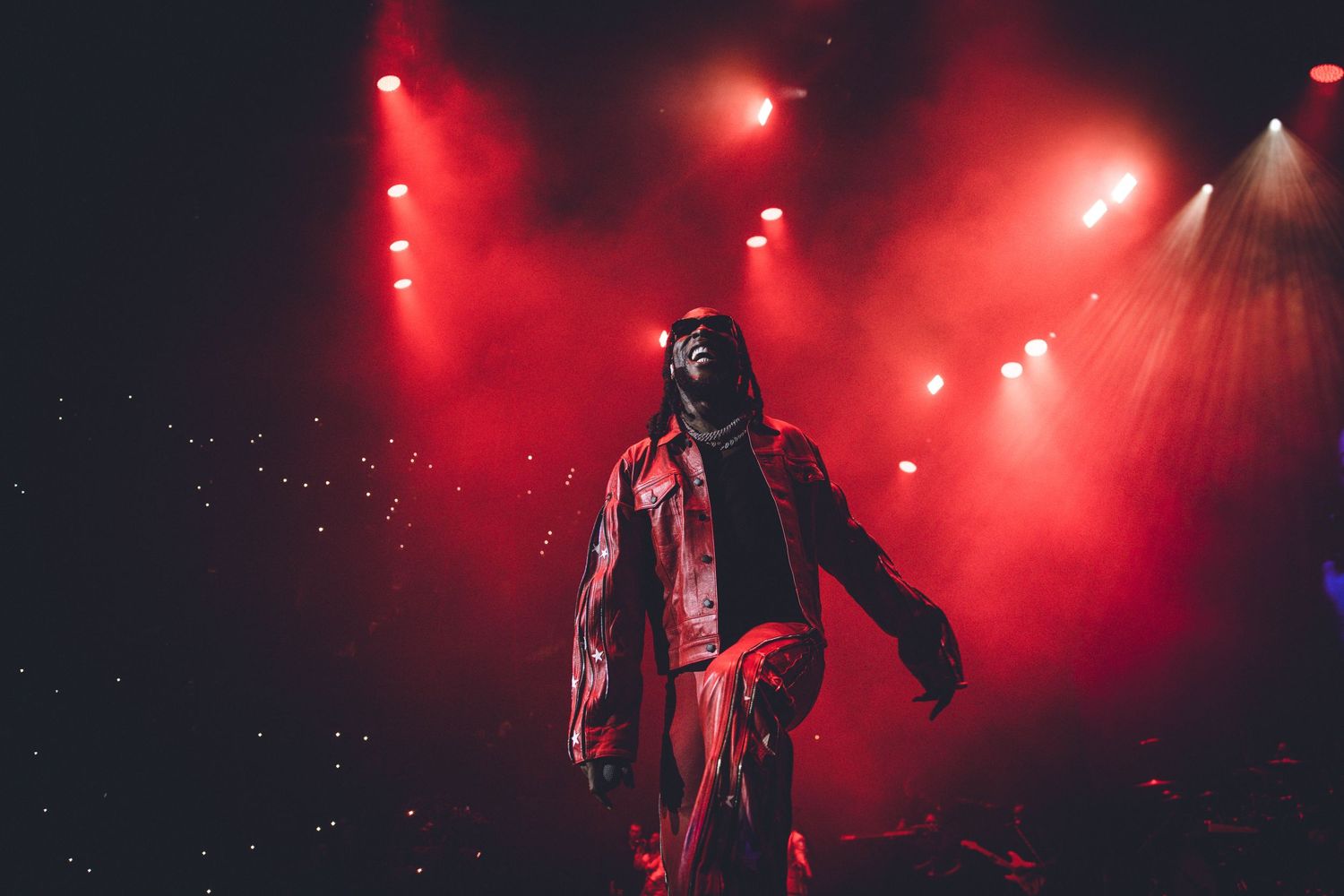 Silhouette of a performer standing on stage bathed in dramatic red stage lighting and smoke.