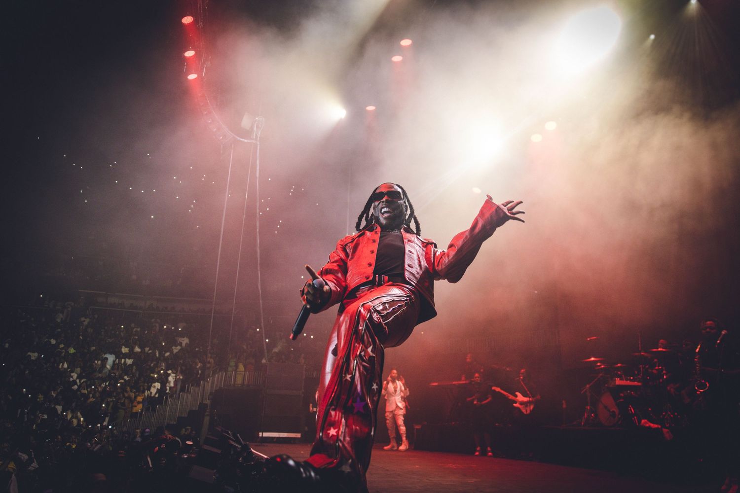 Energetic stage performance with dramatic backlighting and fog effects.