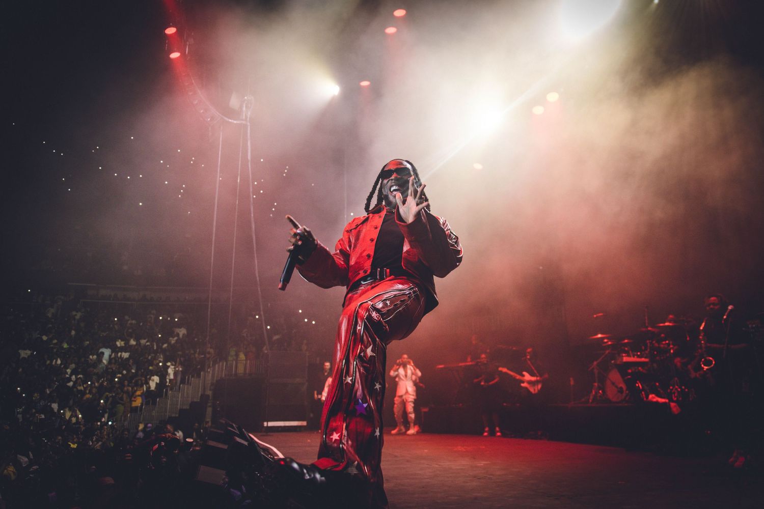 Dynamic stage performance with fog effects and dramatic red and white lighting.