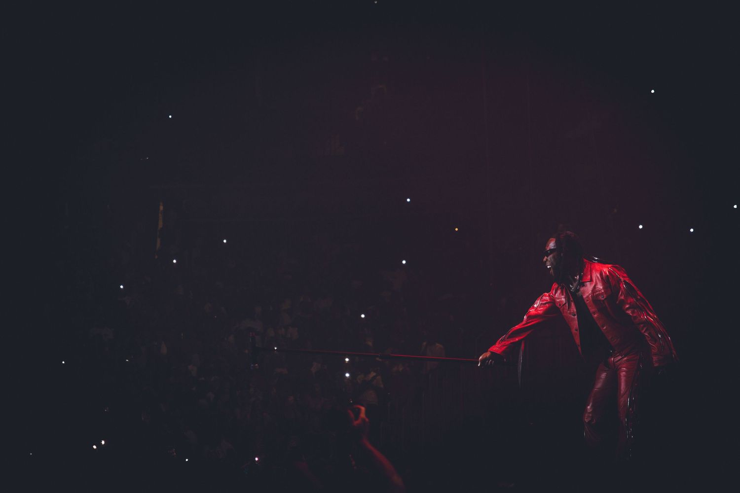 Dramatic concert scene with performer in red outfit against starlit dark background.