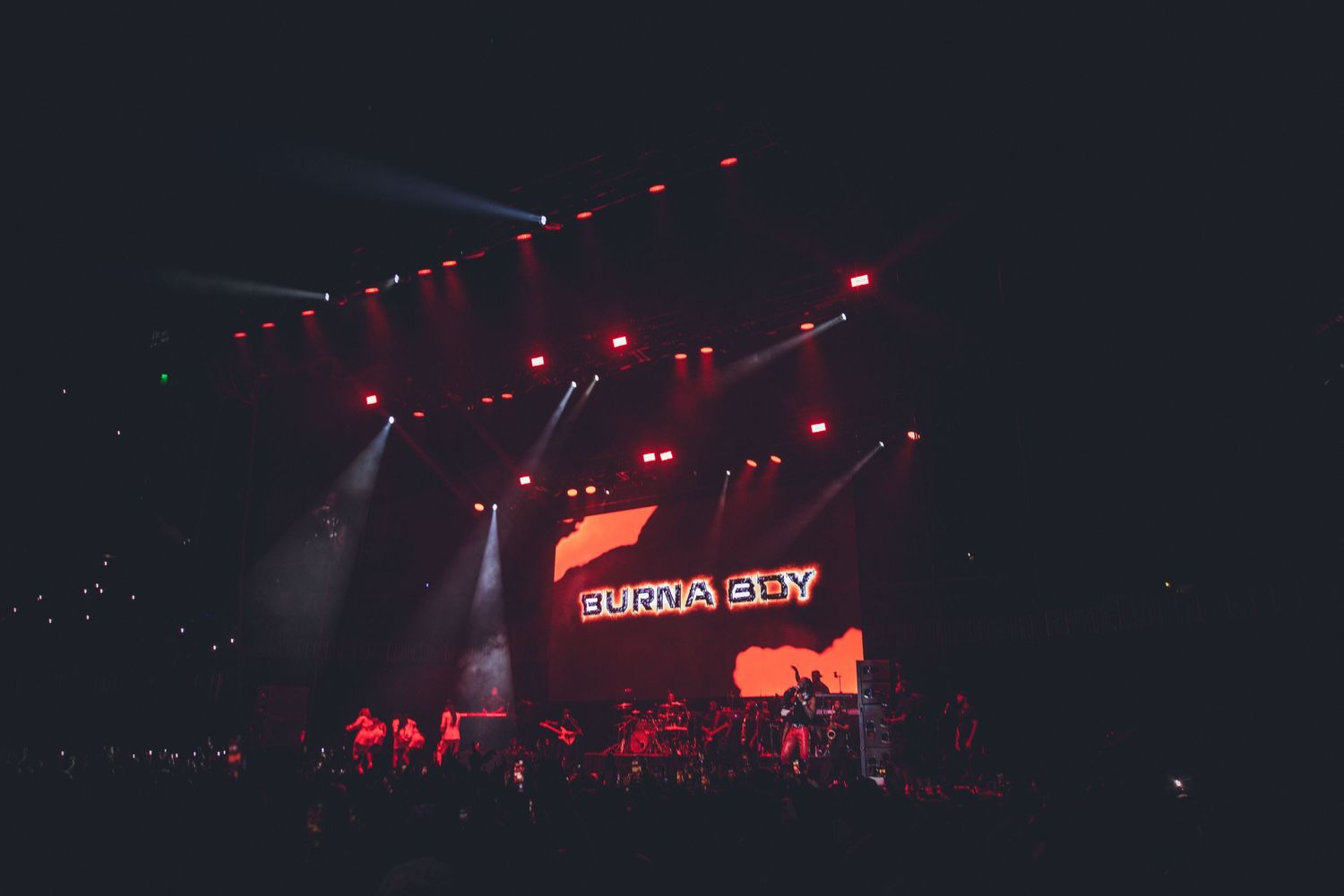 Dark concert stage with red lighting effects and illuminated signage creating moody atmosphere.