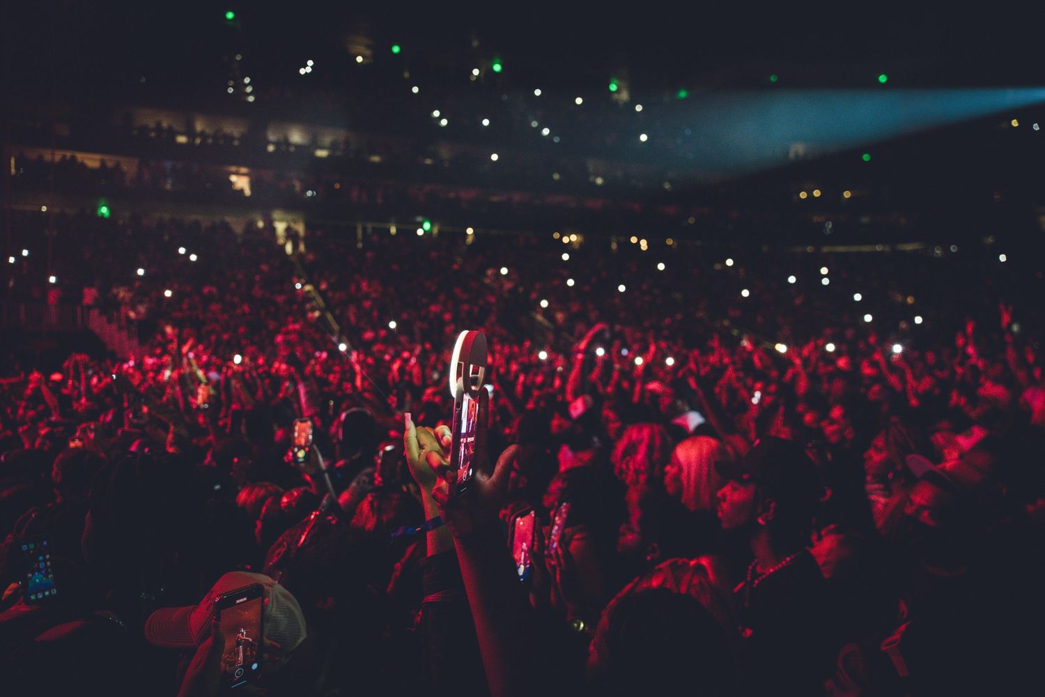 A packed concert venue glows red as crowd and performer create an energetic atmosphere.