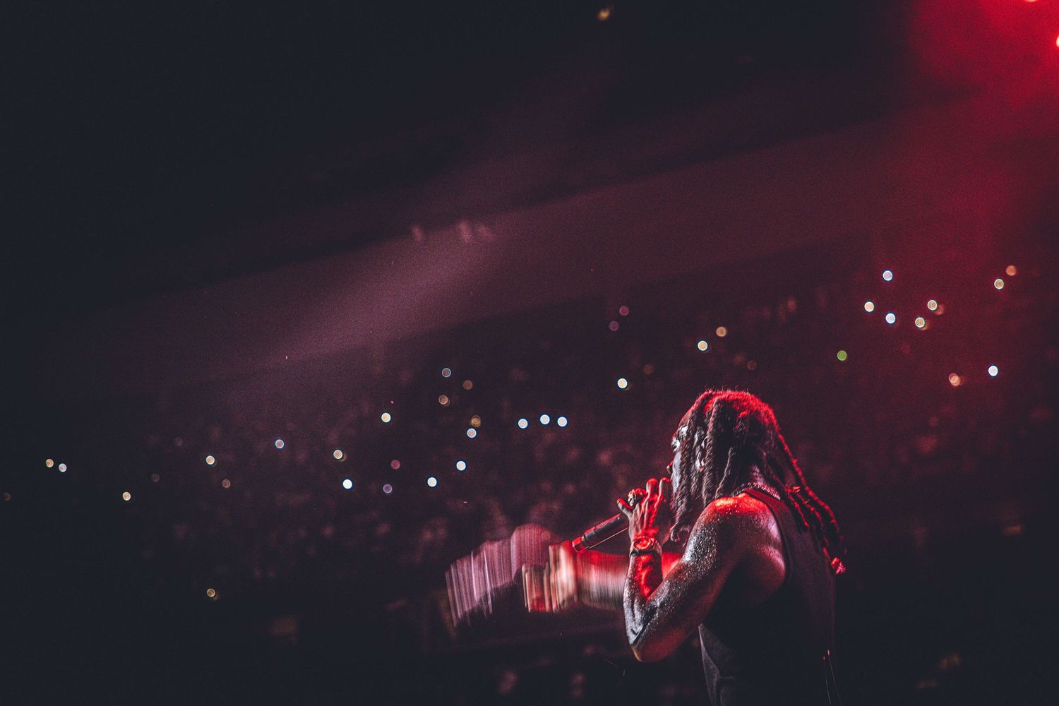 Atmospheric concert scene with red lighting and distant crowd lights creating depth.