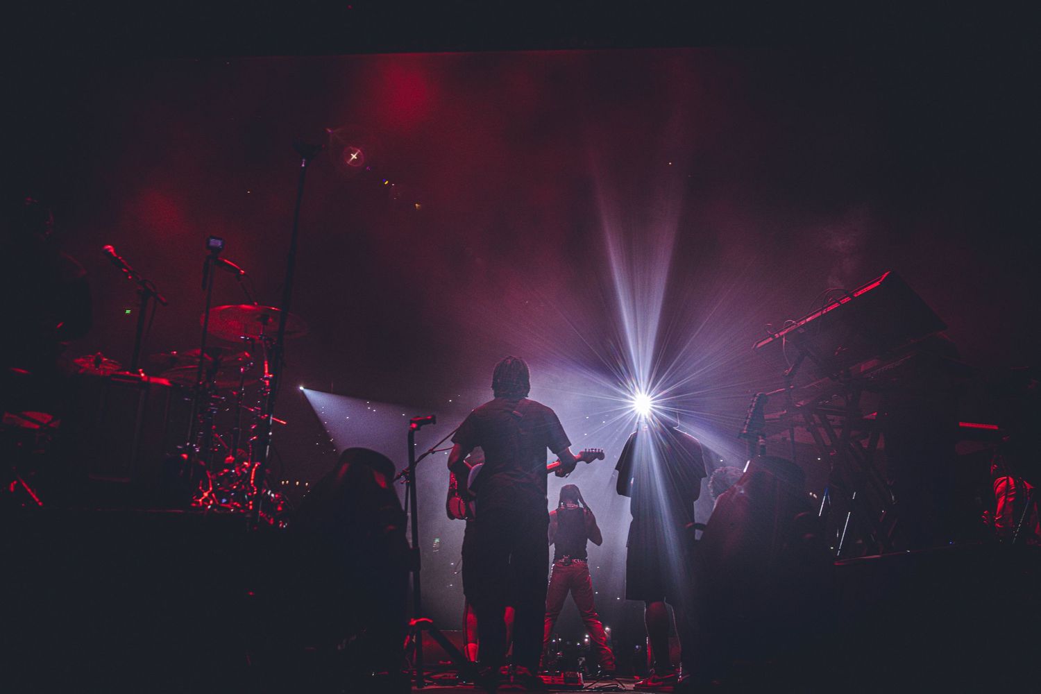 Wide panoramic view of concert stage with dramatic lighting and fog effects.