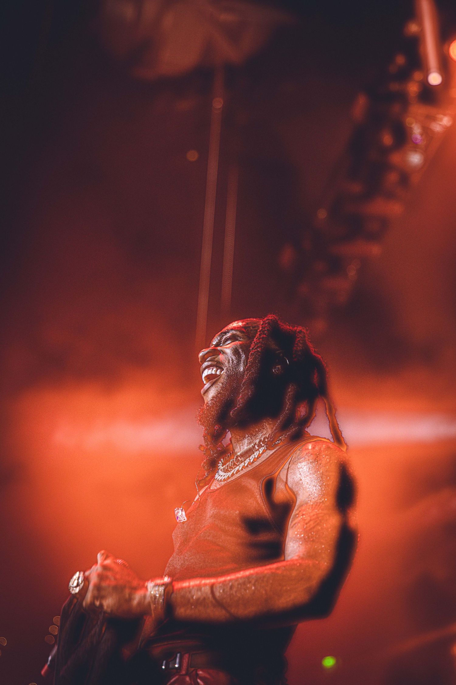 Stage performer bathed in orange lighting showing intense emotion during live show.