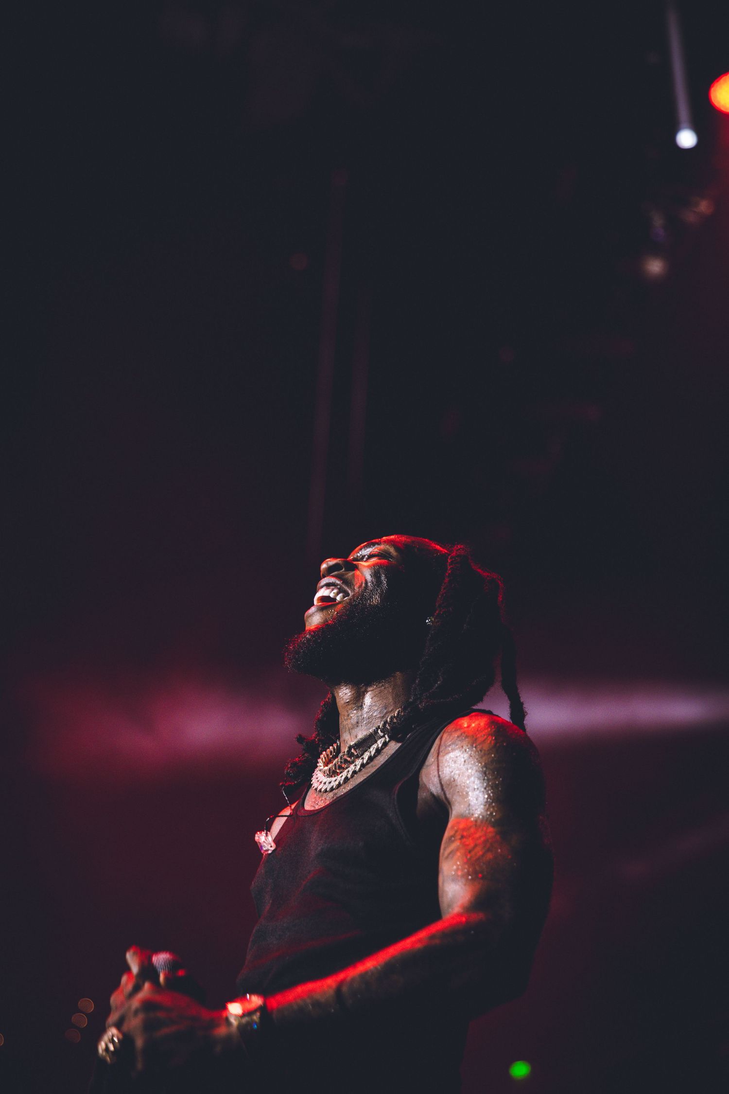 Dramatic performance captured under dark lighting with red spotlights creating moody atmosphere.