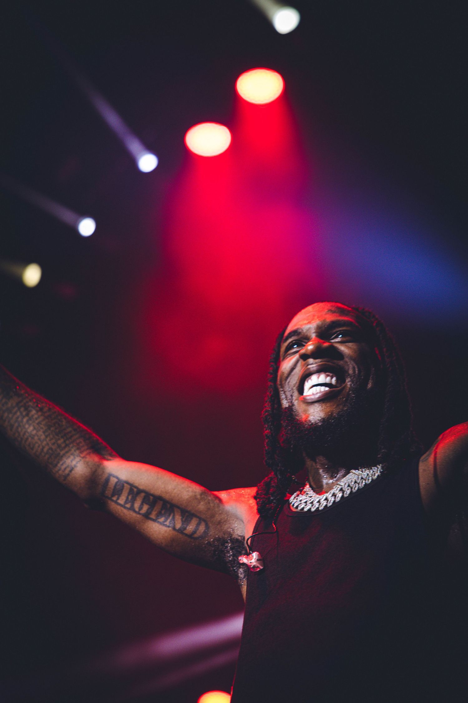 Concert performer illuminated by red and blue stage lighting during an energetic performance at night.