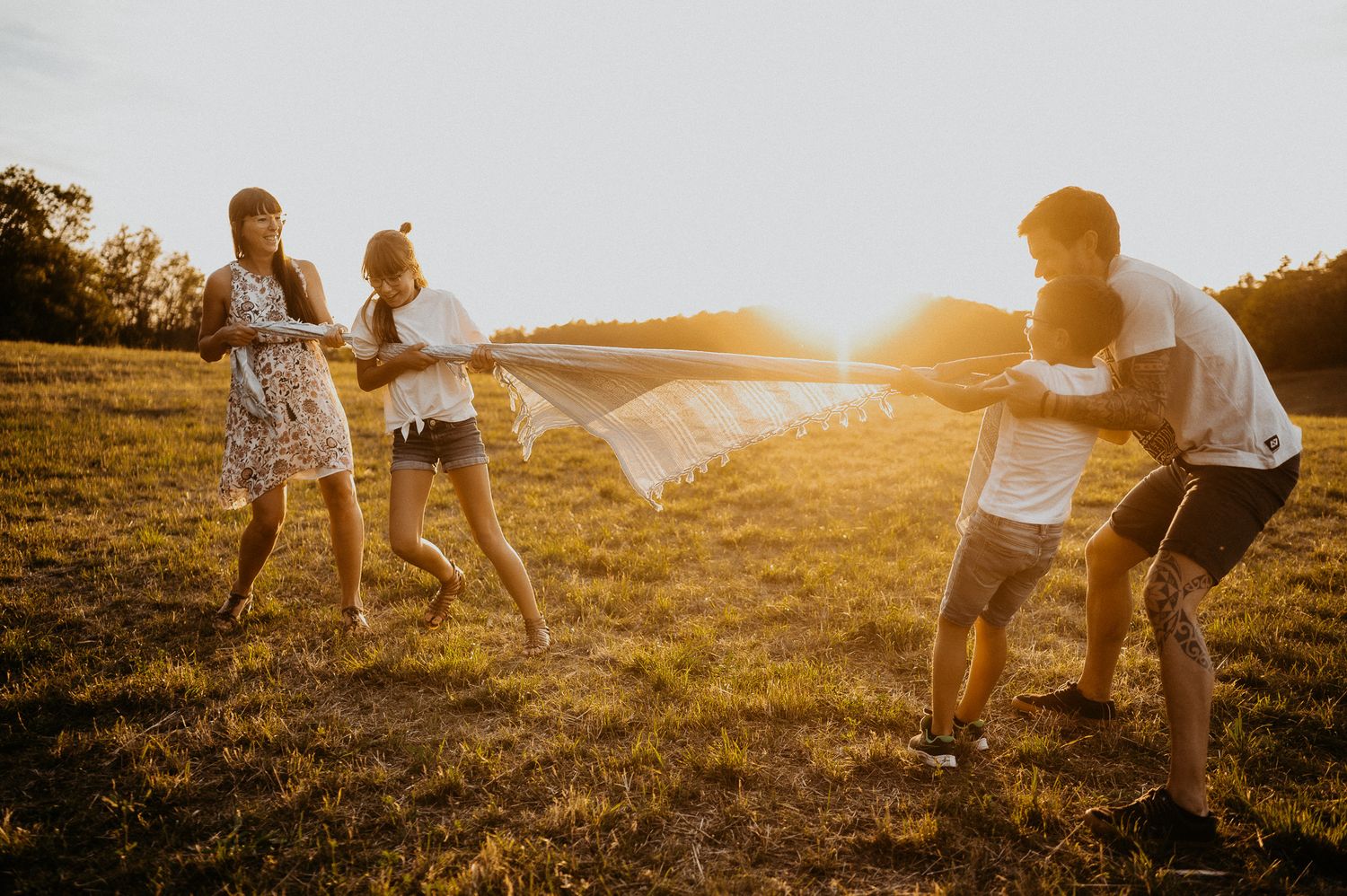 Familie spielt im Sonnenuntergang Tauziehen auf einem Hügel über Jena