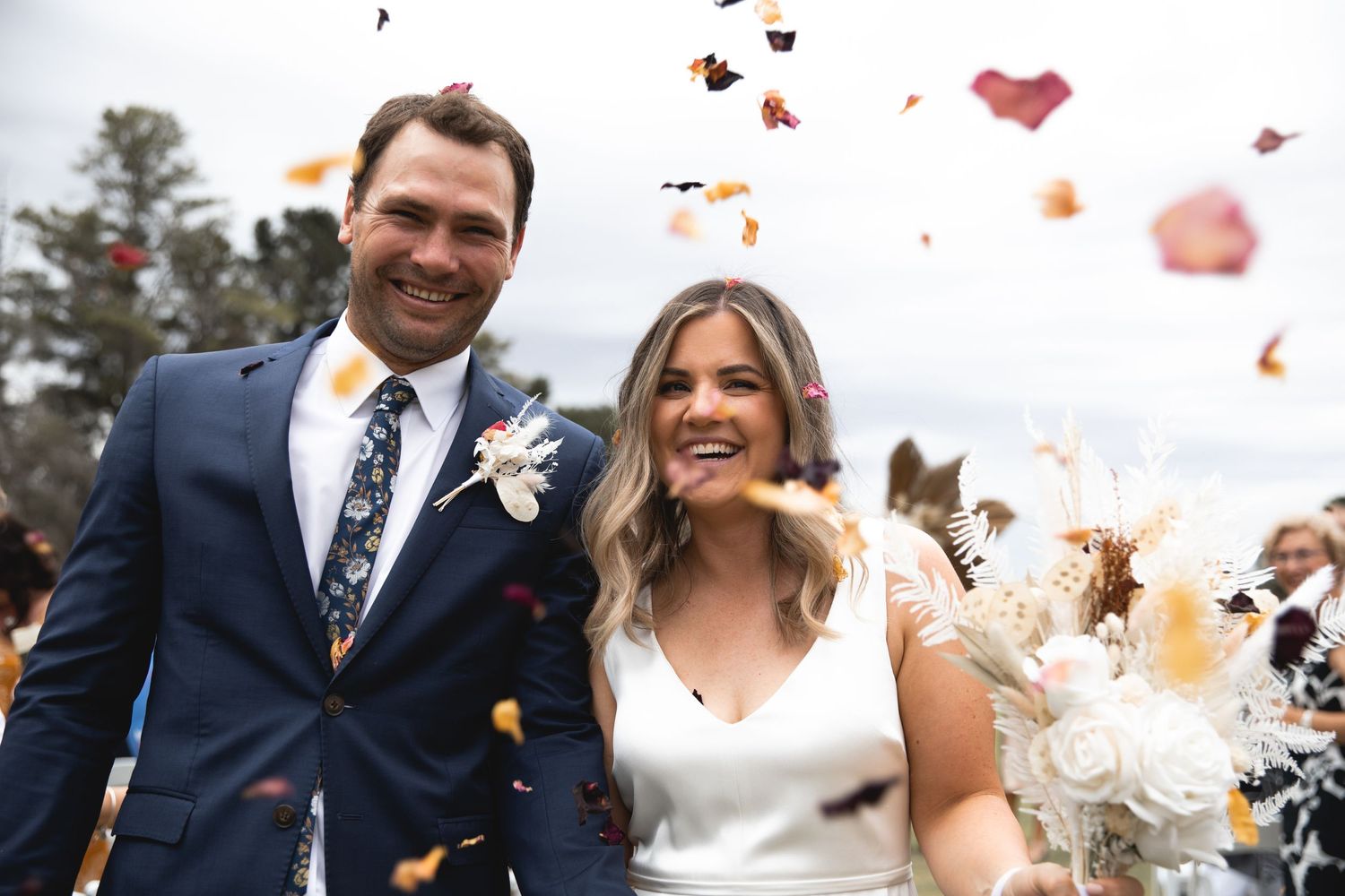 Newlyweds celebrate their joyful wedding day as flower petals float through the air around them.