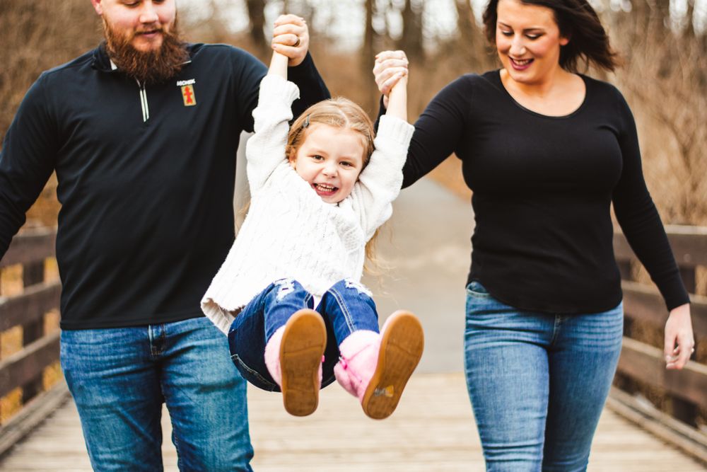 Family having fun swinging and playing on a wooden bridge in autumn.