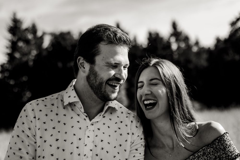 Romantic black and white portrait of a laughing couple in a natural outdoor setting.
