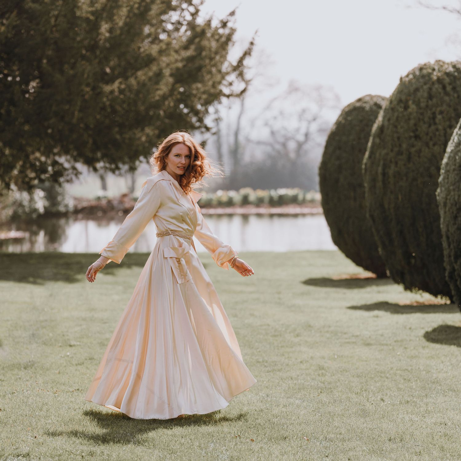 Romantic garden scene with flowing cream dress and landscaped background.