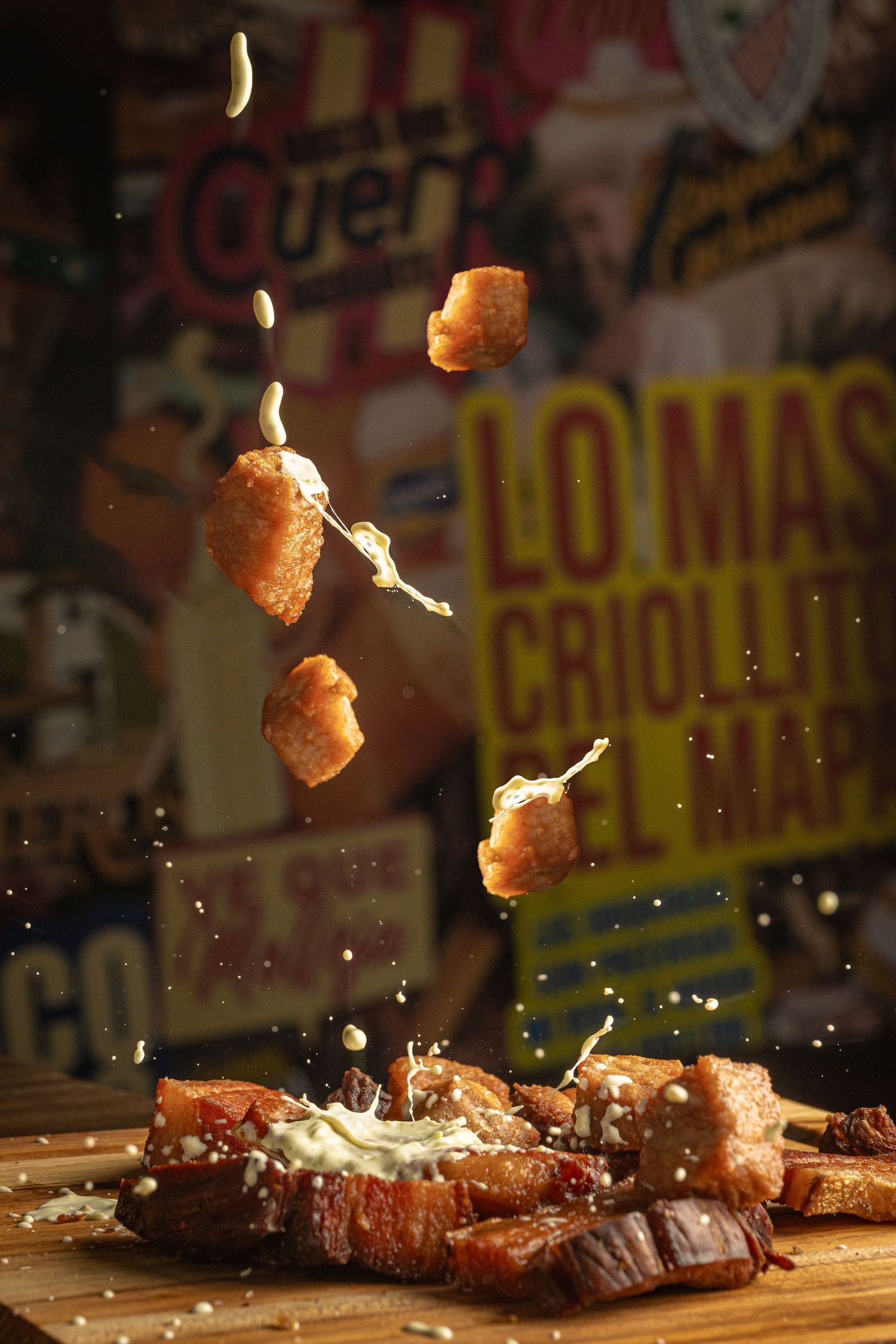 Crispy fried food pieces falling onto a wooden board with melted cheese in a vibrant restaurant setting.