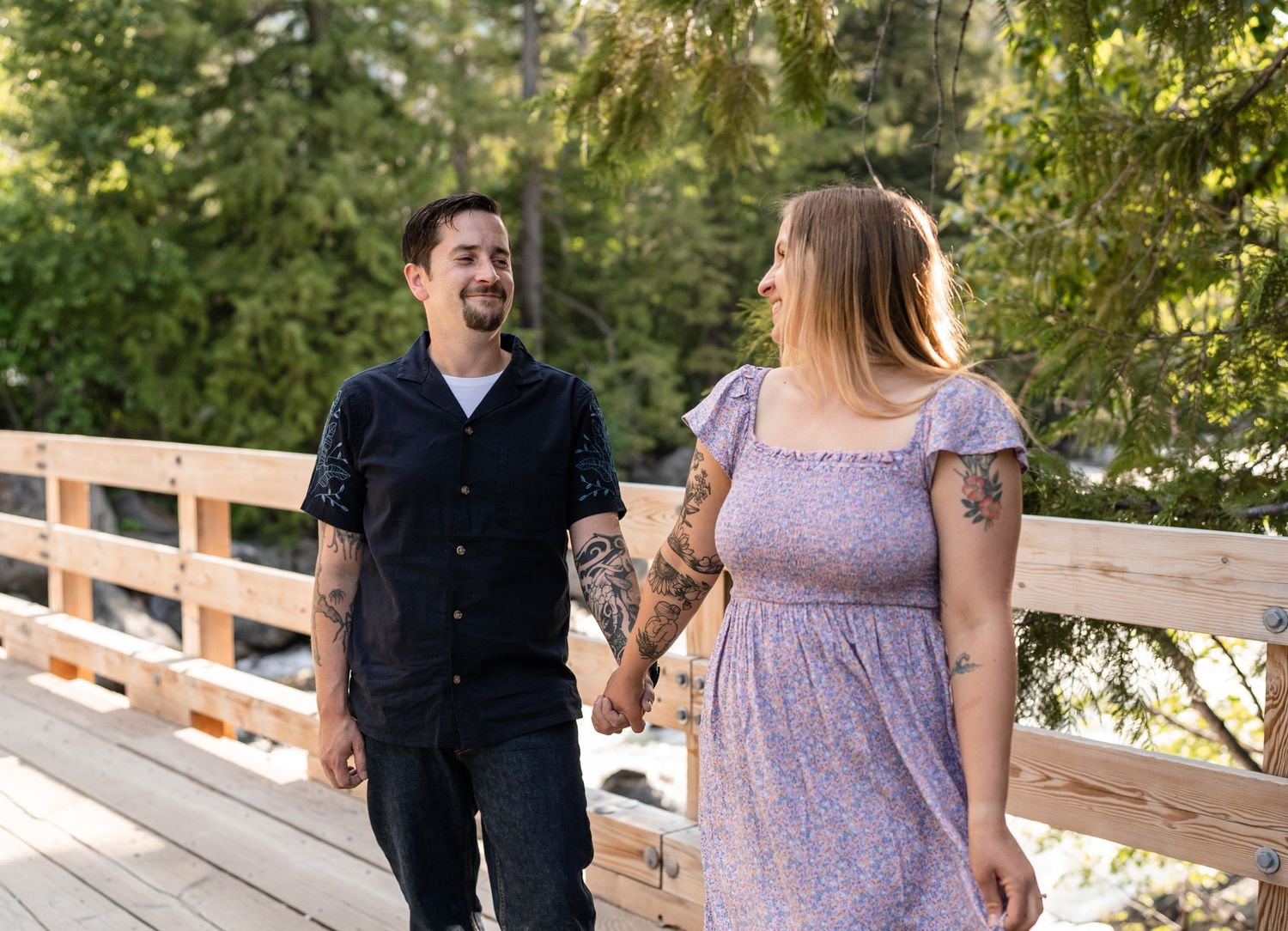 Happy couple sharing a moment on a wooden bridge surrounded by forest scenery.