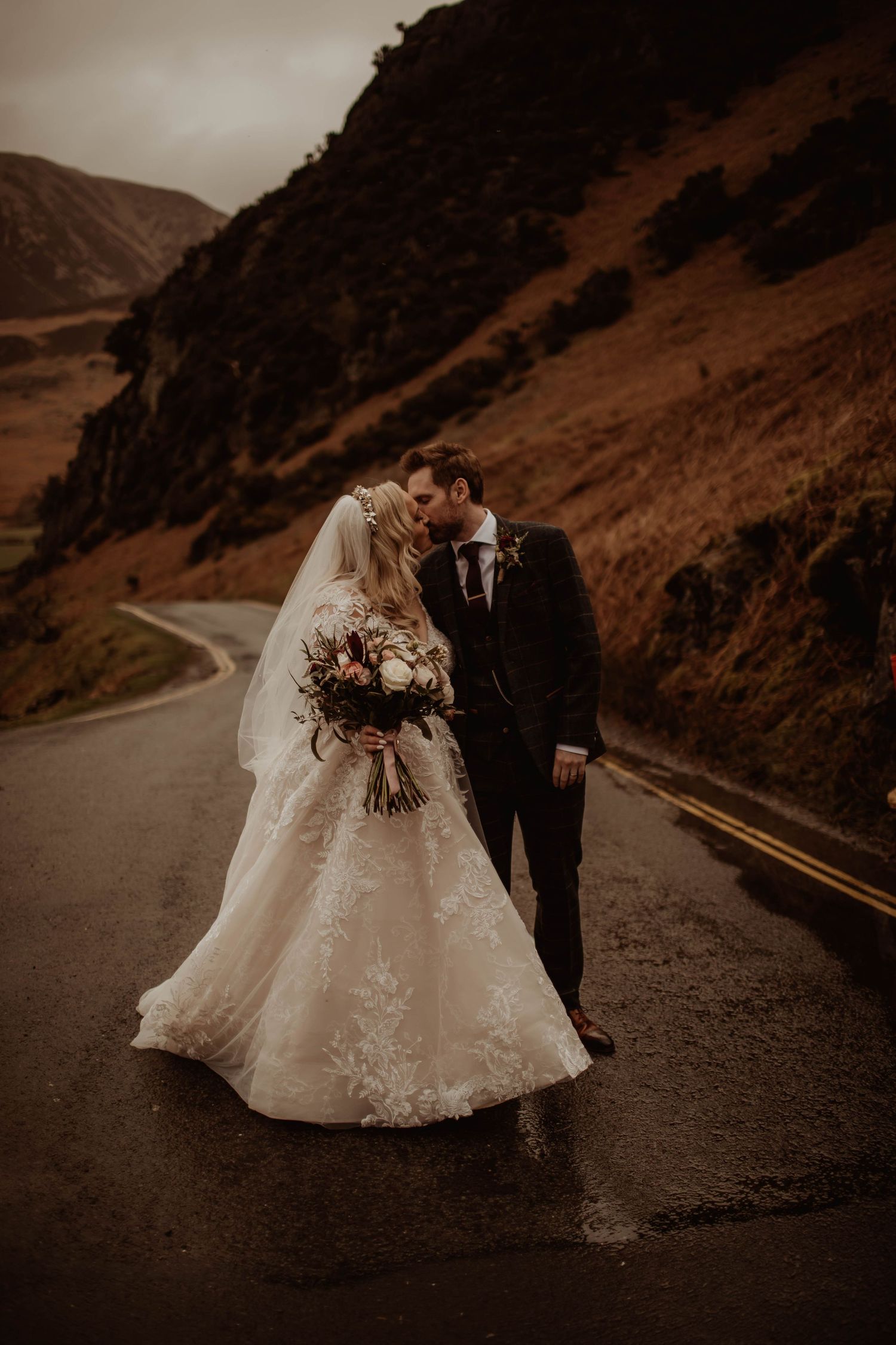 A dramatic wedding photo on a misty mountain road with moody atmosphere.