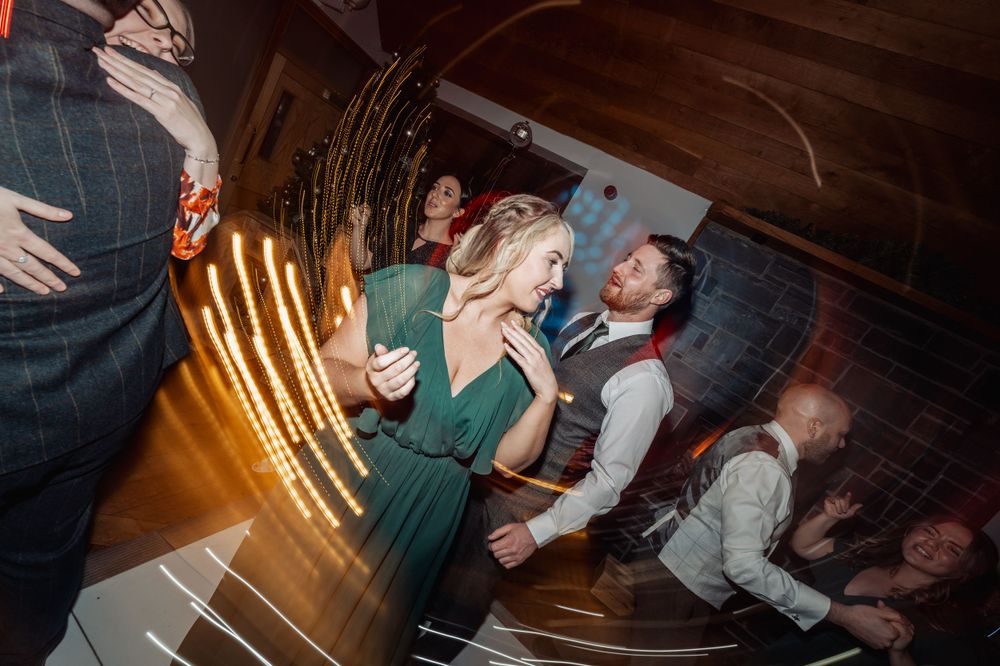 A lively dance floor scene with celebrants in formal attire under warm lighting.