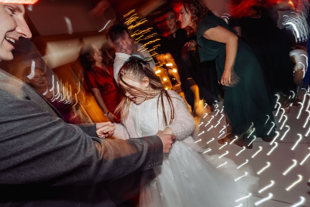 Dynamic reception dance floor moment captured with motion blur and festive lighting.