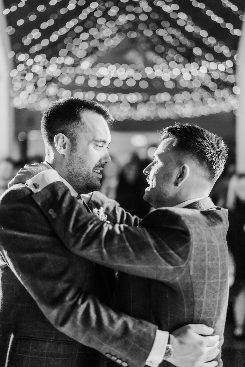 An intimate black and white dance moment under twinkling lights at a celebration.