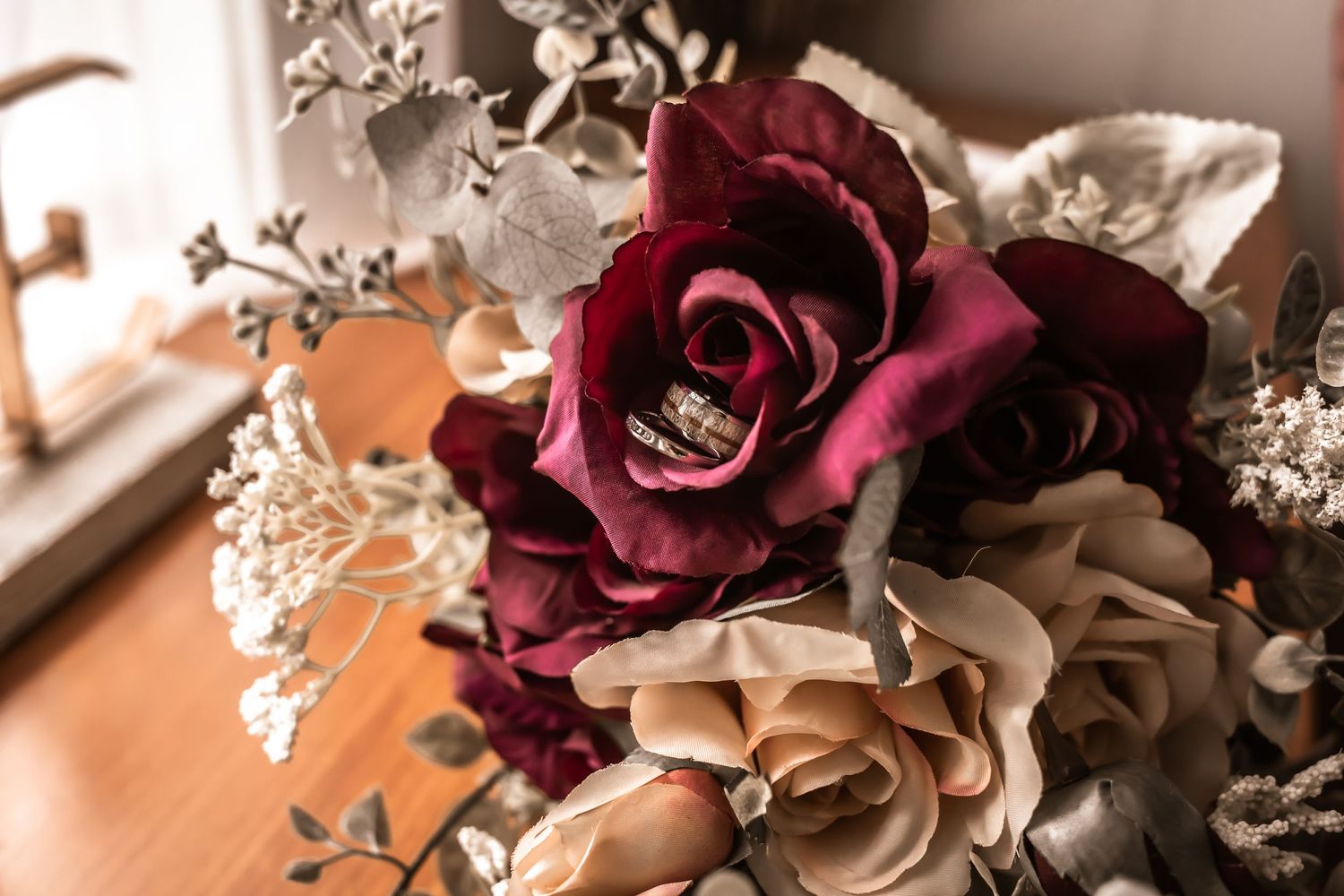 Elegant arrangement of burgundy and cream roses with delicate baby's breath flowers.