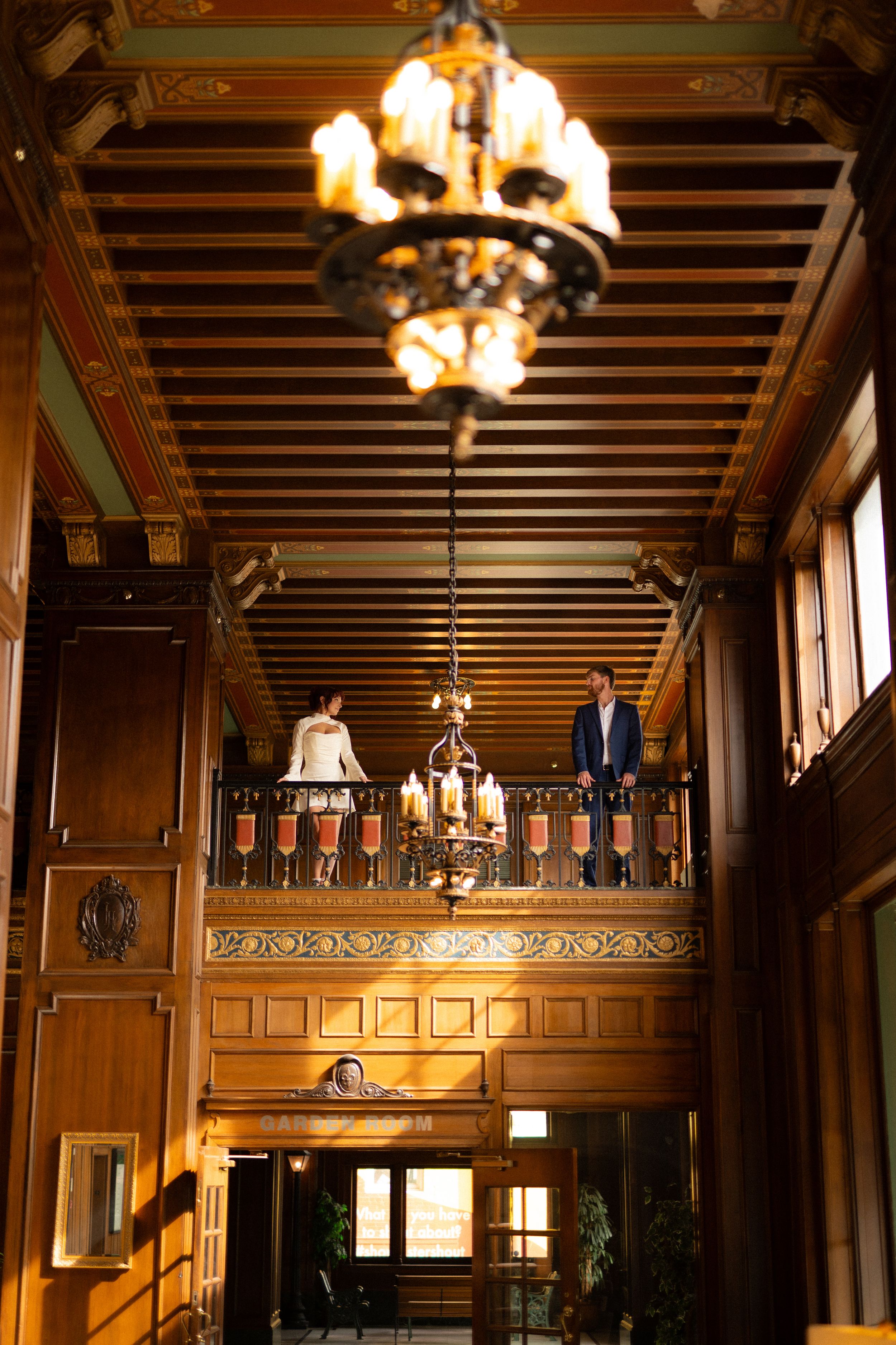 Grand ballroom interior with wooden panels and crystal chandeliers creating warm ambient lighting.